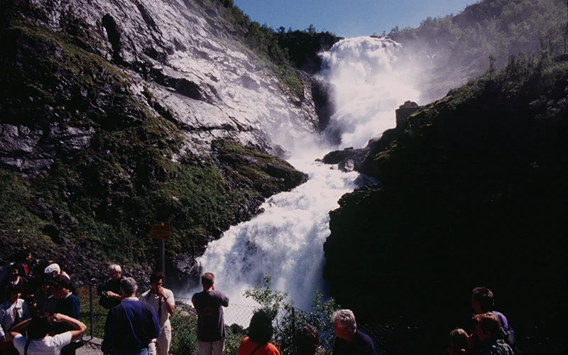 Waterfall on the Flam railway with passengers watching from the viewing area