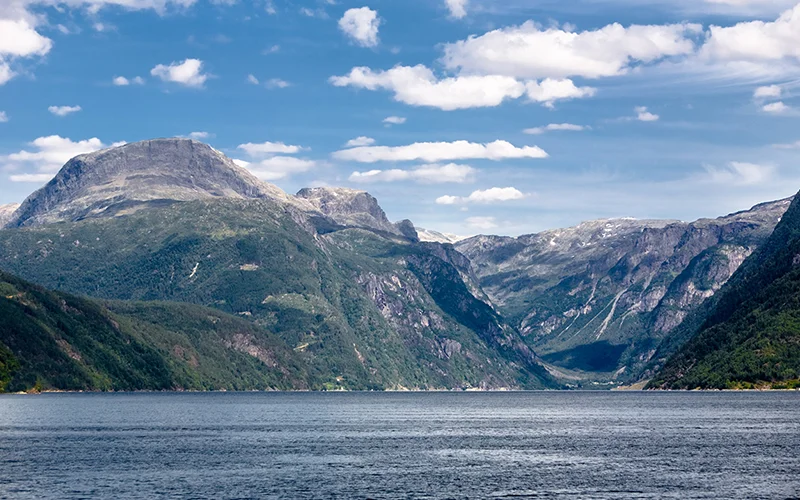 A Norwegian fjord between steep mountains under a blue sky