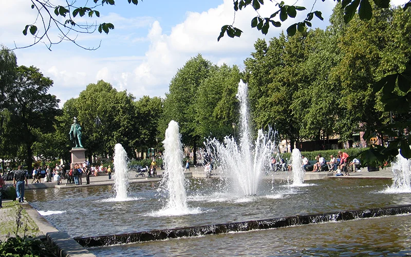 Fountains in a park in Oslo with people sitting around them