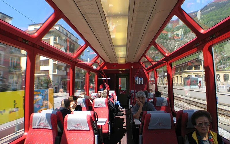 Interior of a panoramic Swiss train with red seats and curved windows