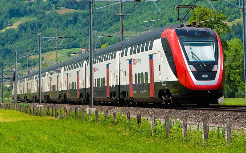 Double-deck Swiss train passing a green hillside