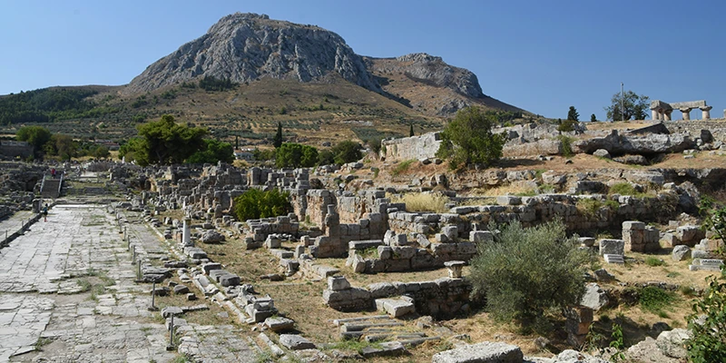 The rock of Acrocorinth rising above the ancient road and ruins