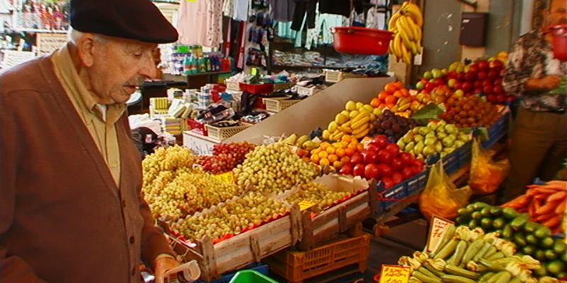 A vendor at a fruit and vegetable stall in the Heraklion market