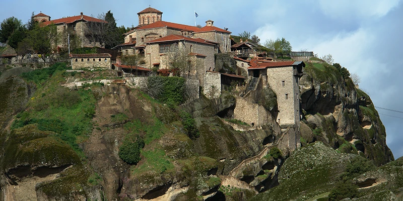 A Meteora monastery with red-tiled roofs on its rock summit
