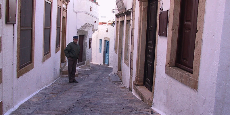 A resident walking a narrow whitewashed lane in Chora