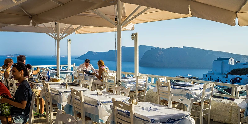 Terrace restaurant with umbrellas and a caldera view