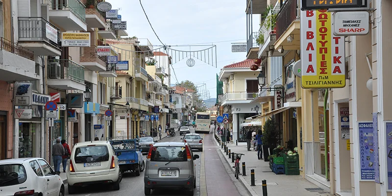 Shops and parked cars on a street in a small Greek town