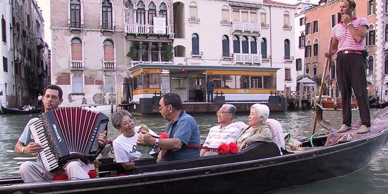 A singing gondolier glides by in a narrow Venetian canal